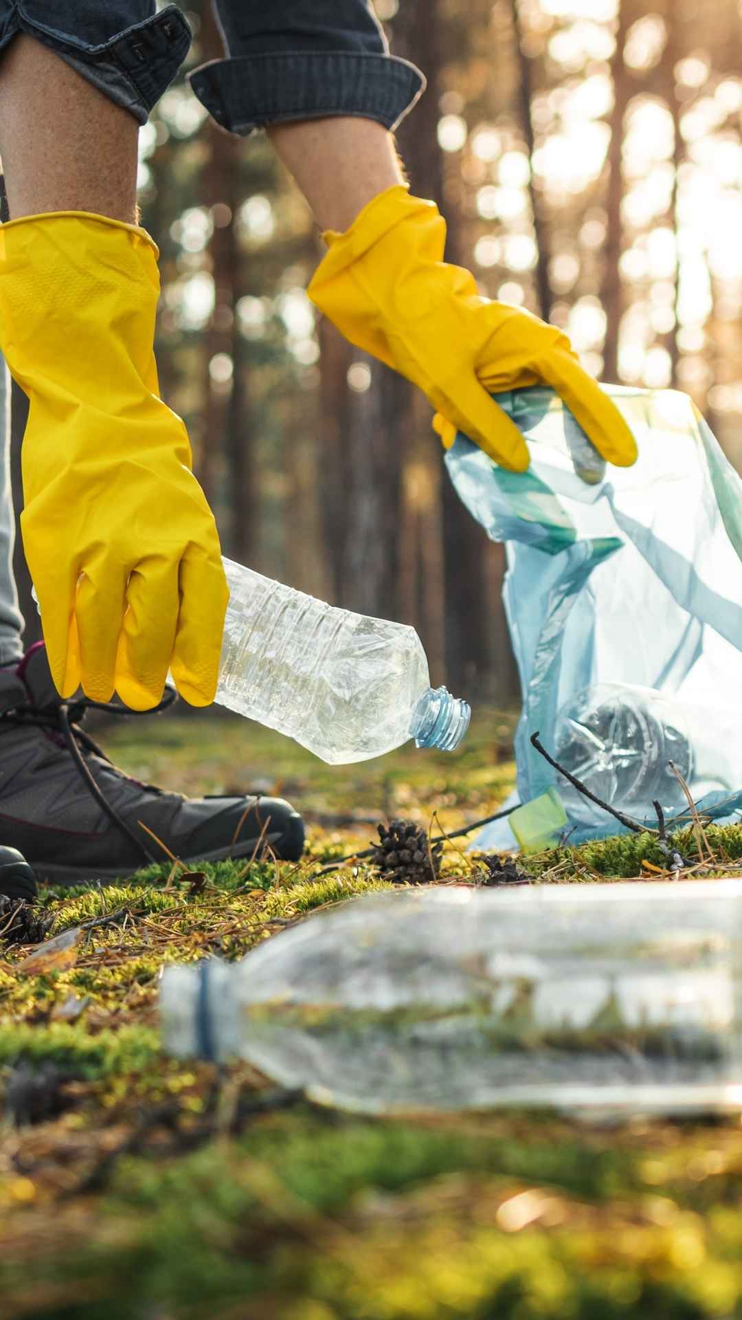 Eine Person mit Gummihandschuhen und Müllbeutel im Wald die Müll sammelt eine der schönsten Formen des Karma Yogas