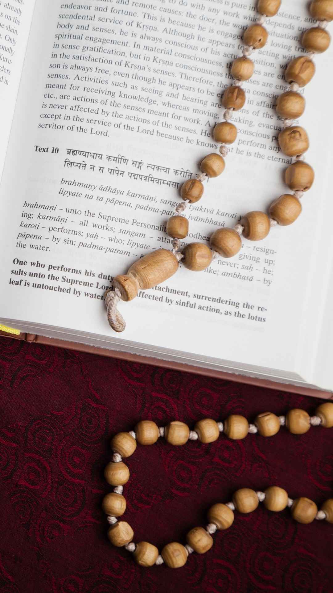 Mantras in einem Buch mit einer Holz Mala zum Mantra Rezitieren dabei 